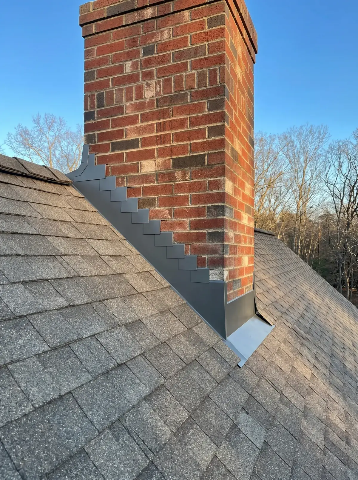 New Black or Brown step flashing counter-flashed into the mortar joints where chimney meets roof